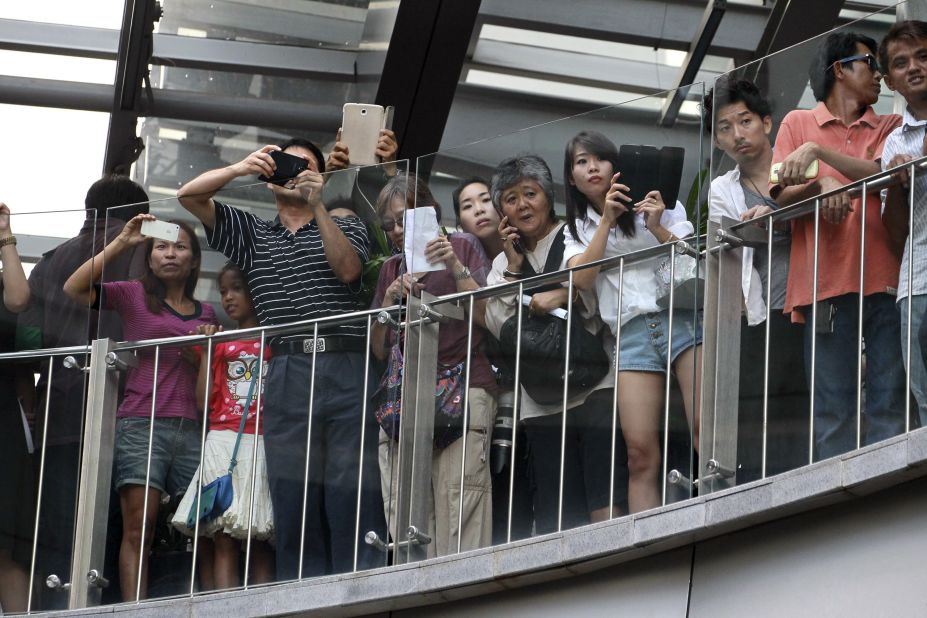 Onlookers at a Bangkok shopping mall watch as protesters shout  "Freedom!" and "Democracy!" on June 1.