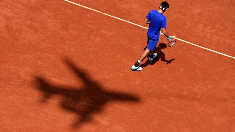 An airplane's shadow is seen on the red clay of Roland Garros as tennis player Leonardo Mayer walks to the service line Saturday, May 31, in Paris. Mayer was playing Rafael Nadal, who he lost to in the third round of the French Open.