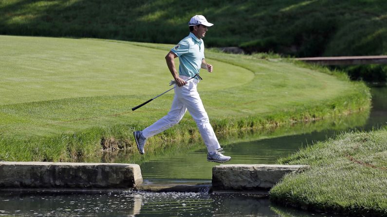 Golfer Mike Weir runs hops over a water hazard Friday, May 30, during the second round of the Memorial Tournament in Dublin, Ohio. Weir missed the cut of the event, which was won by Hideki Matsuyama in a playoff.