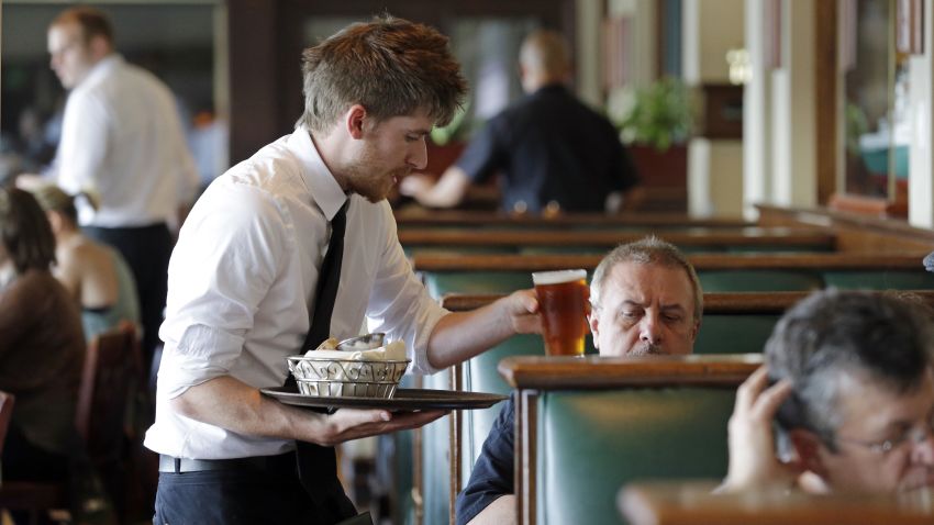 Waiter Spencer Meline serves a customer at Ivar's Acres of Clams restaurant on the Seattle waterfront Wednesday, May 14, 2014. While the Seattle mayor is proposing to raise the minimum wage to $15 in the coming years to the highest level in the nation, some activists say that's too slow and are threatening to take the issue to voters with a ballot measure that would force a raise sooner. As the mayor's plan is being debated by the council, businesses are sounding the alarm that raising the wage too quickly could hurt their revenue and force them to either hire fewer workers or let go more of their employees, while popular restaurateurs have emphatically argued for counting tips in total compensation. (AP Photo/)