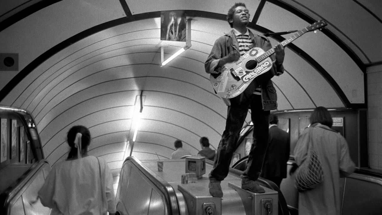 This musician had clambered on an escalator to play his guitar in the early 80s, after Bob Marley had died. The musician had pinned a picture of Marley to the ceiling.