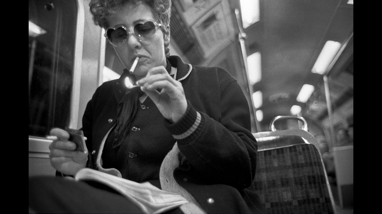 Smoking on the tube was commonplace when Mazzer started his project. Here, a woman in heart-shaped "Lolita" glasses lights up in the early 1980s.