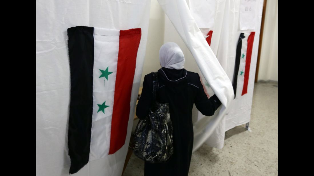 The Syrian flag is seen hanging on a polling booth as a woman goes to cast her ballot in the Syrian presidential election Tuesday, June 3, in Damascus, Syria. The election took place while civil war still rages in the country, and only in areas controlled by the regime of current President Bashar al-Assad.