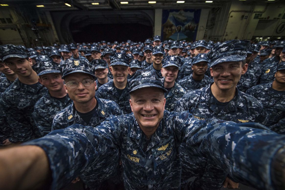 U.S. Navy Capt. Greg Fenton, commanding officer of the USS George Washington, takes a photo in the aircraft carrier's hangar bay after a promotion ceremony Friday, May 30, for 275 sailors behind him. 
