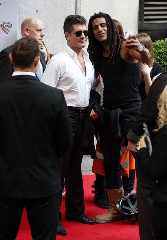 Television personality Simon Cowell, left, poses for a selfie Monday, June 2, as he arrives at the Savoy Hotel in London for the Health Lottery Tea Party charity fundraiser.