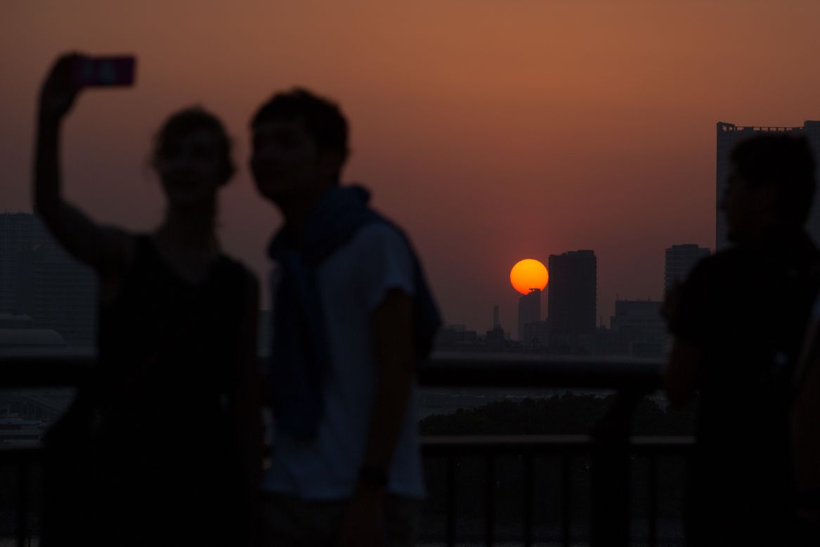 Two people take a selfie as the sun sets over the Tokyo skyline on Saturday, May 31.