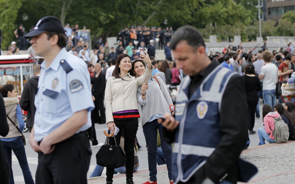 Two women take a selfie together as Turkish policemen stand guard near Gezi Park in Istanbul's Taksim Square on Saturday, May 31. Taksim Square was the flashpoint of anti-government demonstrations last year. Activists called for more protests on the one-year anniversary, but the park <a href="http://www.cnn.com/2014/05/31/world/europe/turkey-cnn-reporter-harassed/index.html">was closed off</a> by police.