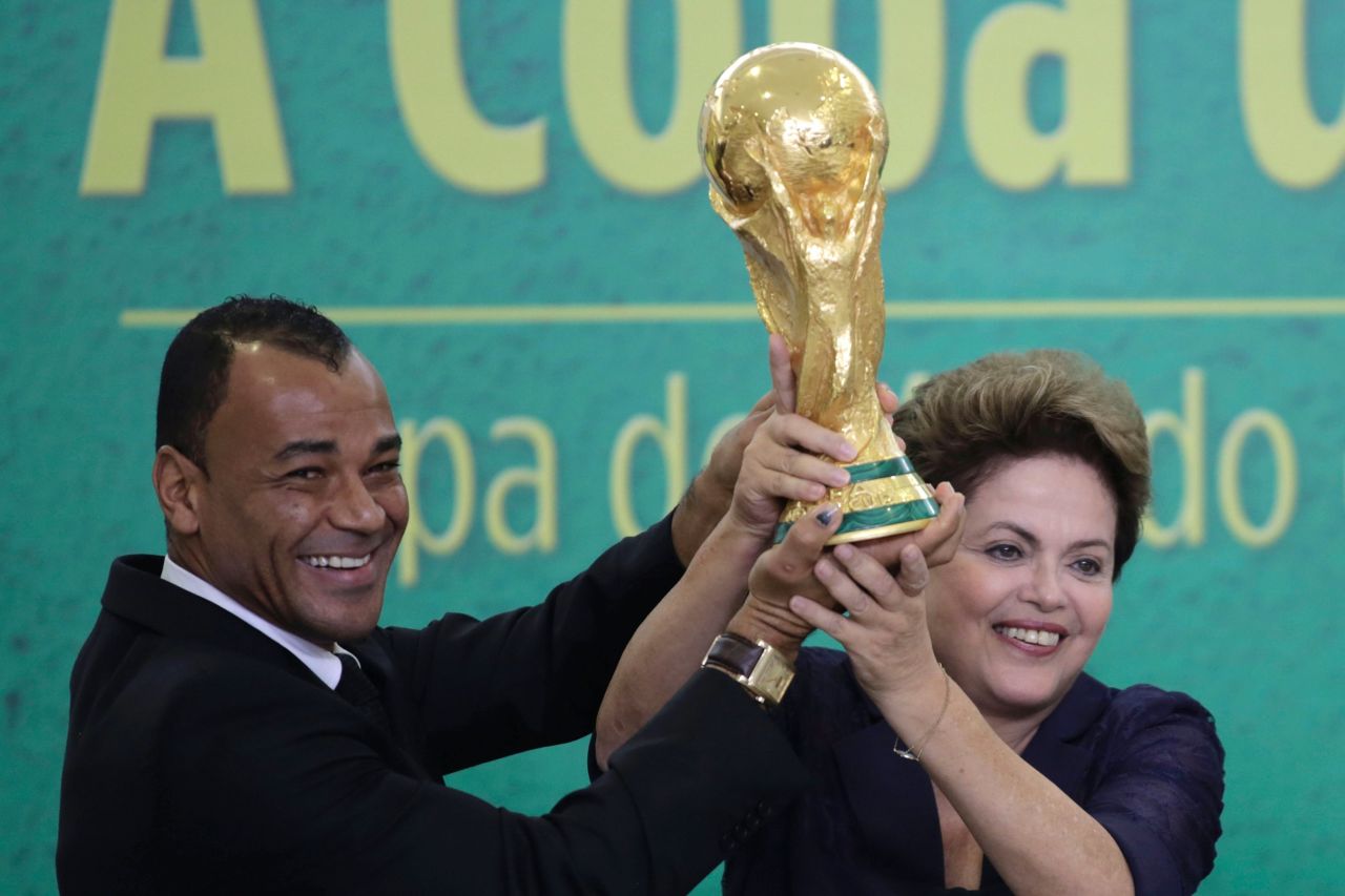 Former Brazilian soccer player, Cafu, and President Rousseff lift the trophy after it was officially presented to her.