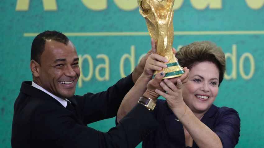 Former Brazilian soccer player Cafu and Brazil's President Dilma Rousseff lift the 2014 World Cup trophy after it was officially presented to Rousseff by FIFA President Sepp Blatter at a ceremony at the Planalto presidential palace, in Brasilia, Brazil, Monday, June 2, 2014. 
