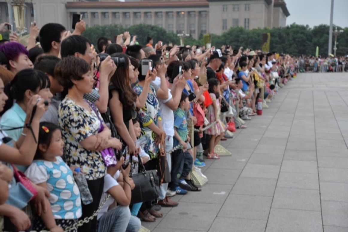 Tourists in Beijing take photos of the daily flag lowering ceremony at Tiananmen Square on June 4.