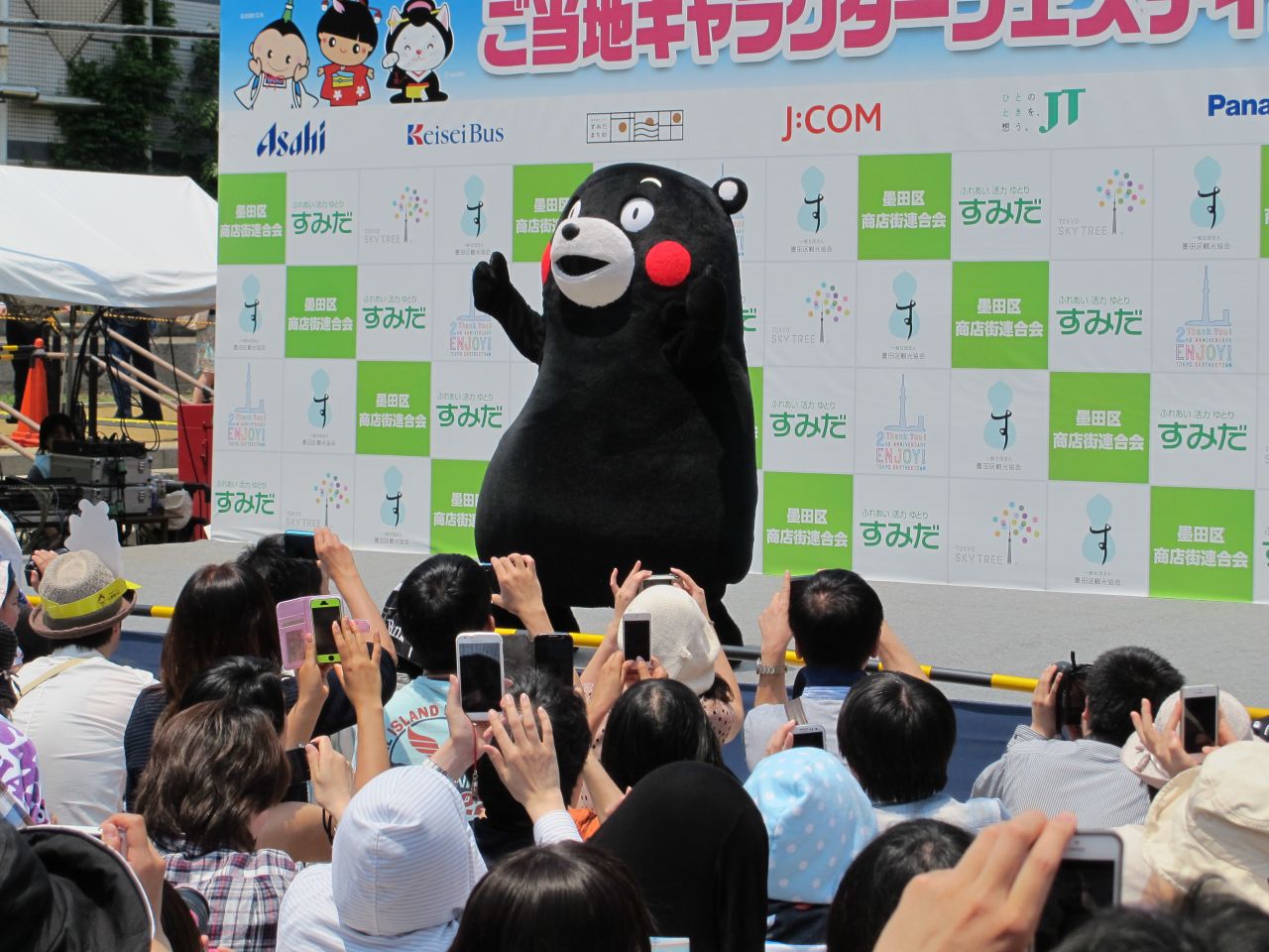 Kumamon, a rosy-cheeked silent black bear waves and dances to music as his fans snap photos. Kumamon is a ubiquitous presence in Japan, advertising everything from food and drinks to video games, and of course, his prefecture of origin, Kumamoto.
