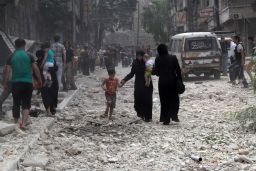 People make their way amid rubble in a street after a reported barrel bombing by government forces in June 2014 in Aleppo's Kallaseh district.