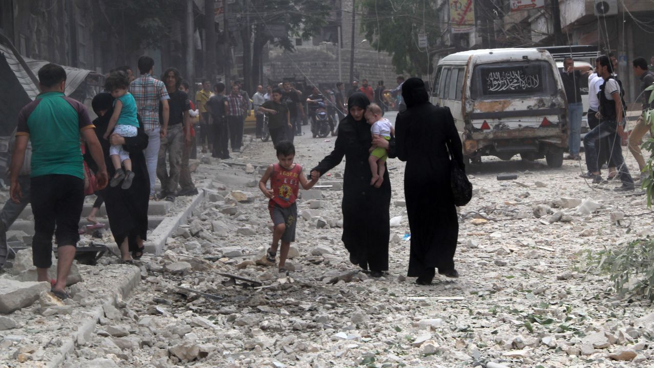 People make their way amid rubble in a street after a reported barrel bombing by government forces in June 2014 in Aleppo's Kallaseh district.