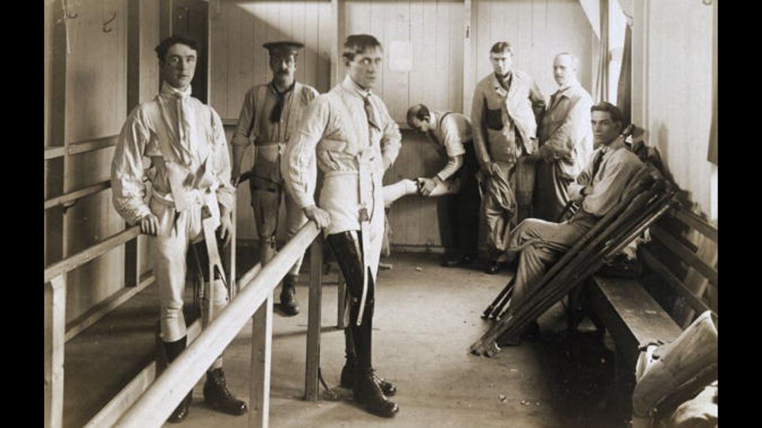 Postcard of British soldiers using parallel bars to help them learn to walk with their artificial legs. Image was probably taken at Queen Mary's Convalescent Auxiliary Hospital, a specialized orthopedic hospital that opened in London in 1915. 