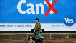 Colin MacDonald Provan walks his dog Colleen down Glasgow High Street past a Yes referendum campaign billboard On May 20, 2014 in Glasgow, Scotland. 