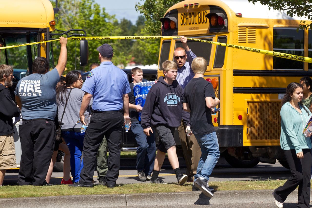 Buses arrive at a grocery store parking lot in Wood Village on June 10 to reunite students with their parents after the shooting.
