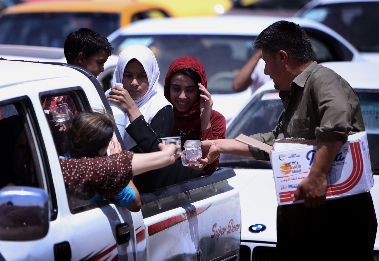 Iraqi families are given water as they gather at a Kurdish checkpoint on June 10.