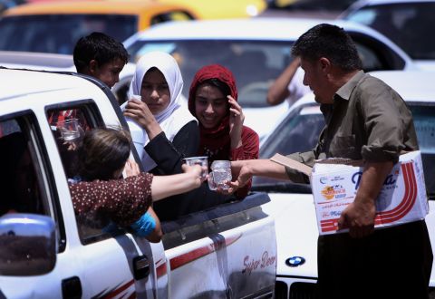 Iraqi families are given water as they gather at a Kurdish checkpoint on June 10.