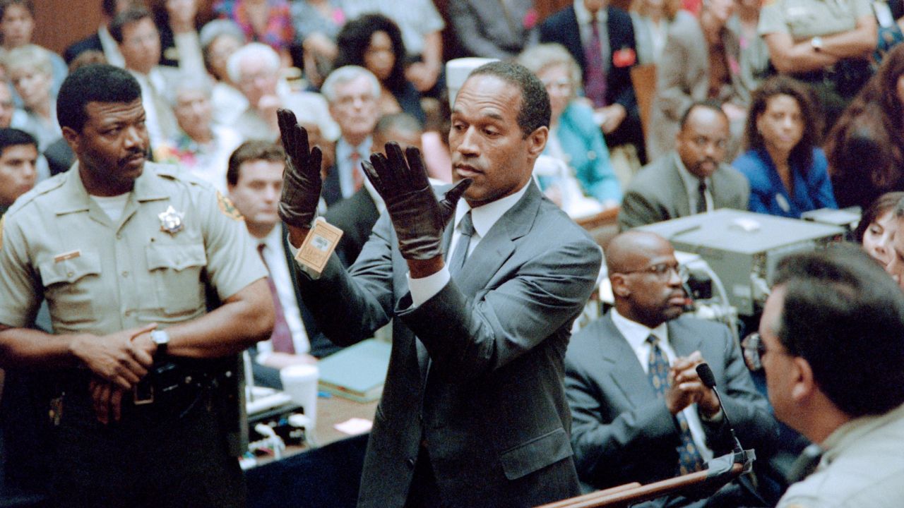 O.J. Simpson looks at a new pair of Aris extra-large gloves which the prosecutors had him put on for the jury 21 June 1995 during his double murder trial in Los Angeles. The gloves were the same type found at the Bundy murder scene and the O.J. Simpson estate.     AFP PHOTO VINCE BUCCI        (Photo credit should read VINCE BUCCI/AFP/Getty Images)