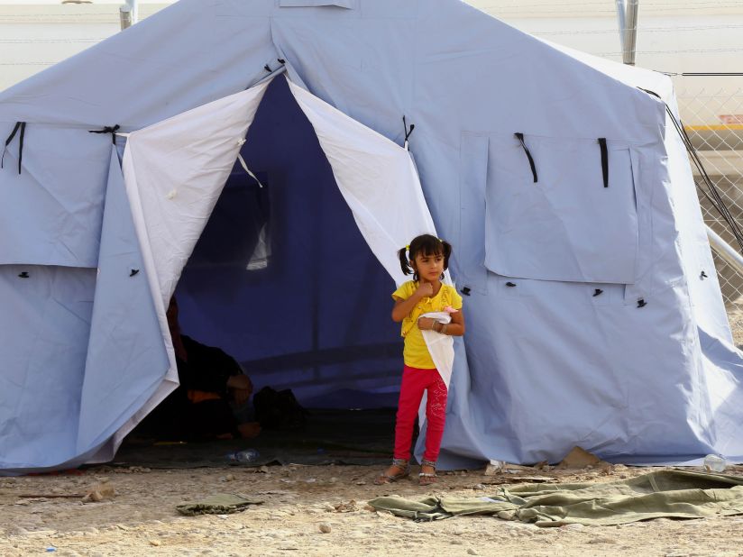 A girl from Mosul stands outside her family's tent at a refugee camp near Erbil on Wednesday, June 11. 