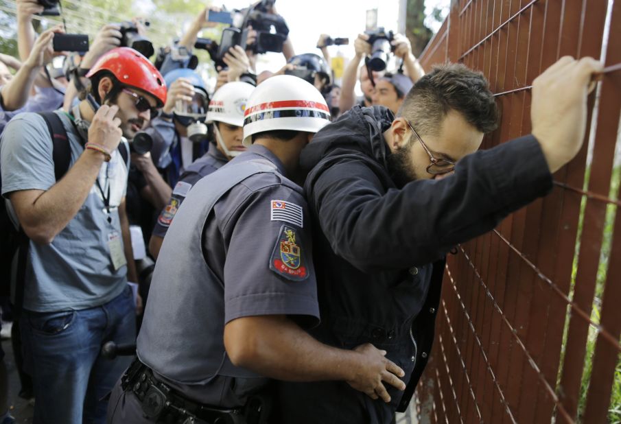 A police officer searches a protester in Sao Paulo.