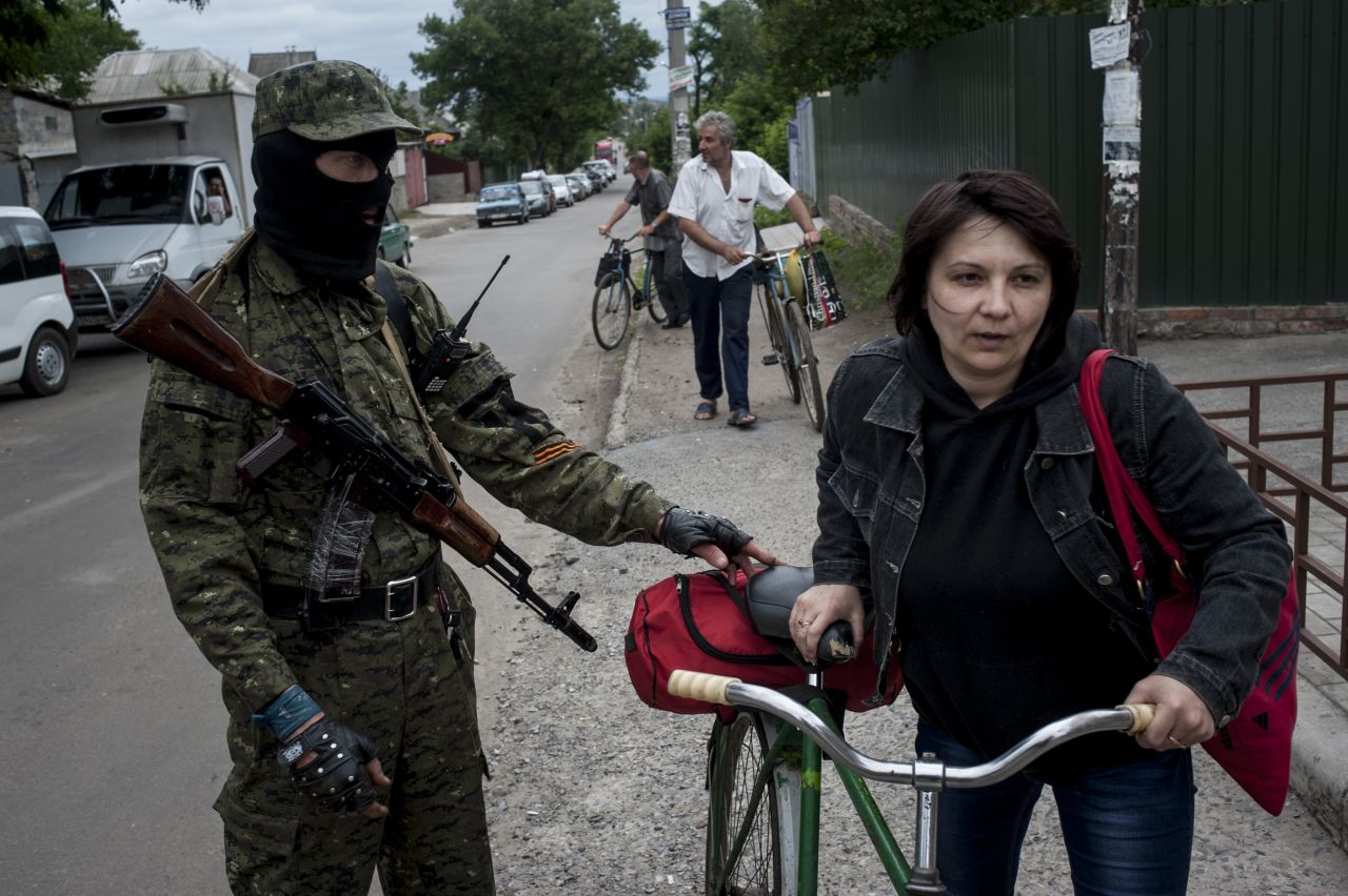 A pro-Russian fighter in Slovyansk checks a woman's documents as she leaves the city on Thursday, June 12.