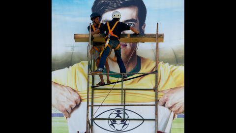 Construction workers put the finishing touches on banners outside of a stadium in Brasilia, Brazil.