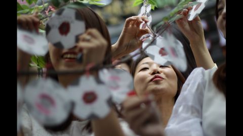 Women attach paper messages on a tree in Seoul, South Korea. The messages wish the national team success in the World Cup.