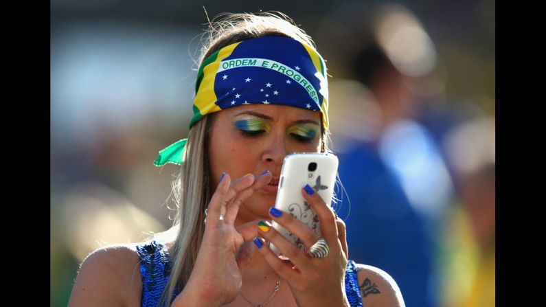 A Brazil fan uses a cell phone before the opening ceremony.