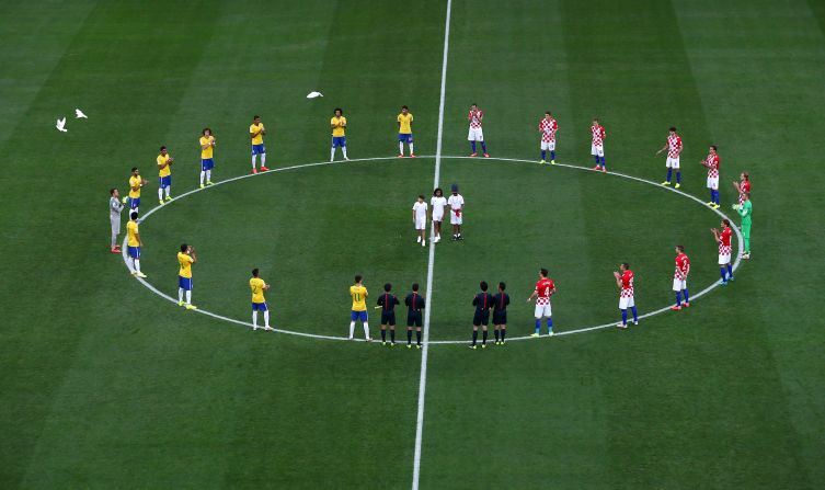 Los jugadores de Brasil y Croacia se sitúan alrededor del círculo central de la cancha mientras varias palomas son liberadas antes del inicio del partido.
