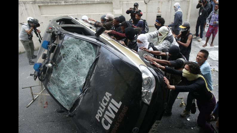 Demonstrators push over a police car.
