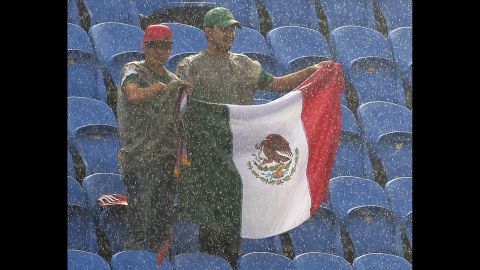 Mexico fans endure heavy rain as they wait for the start of the match. 