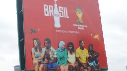 People pass a Coca-Cola billboard referring to the 2014 FIFA World Cup football championship in Brazil, on a road in Nairobi, on June 10, 2014.