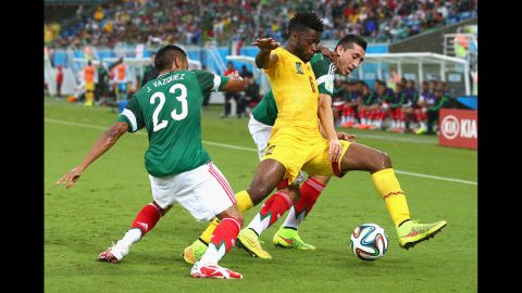 Alex Song of Cameroon is challenged by Mexico's Jose Juan Vazquez, left, and Herrera during the first half.