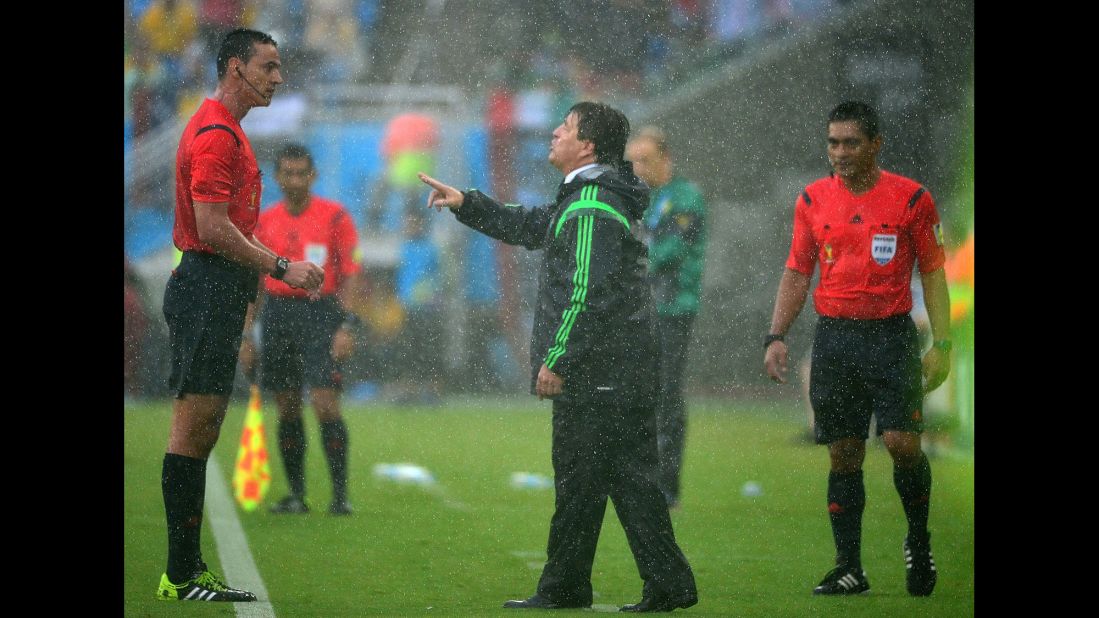 Mexican coach Miguel Herrera, center, speaks to referee Wilmar Roldan during the game. Two Mexican goals were disallowed in the first half after being called offside.