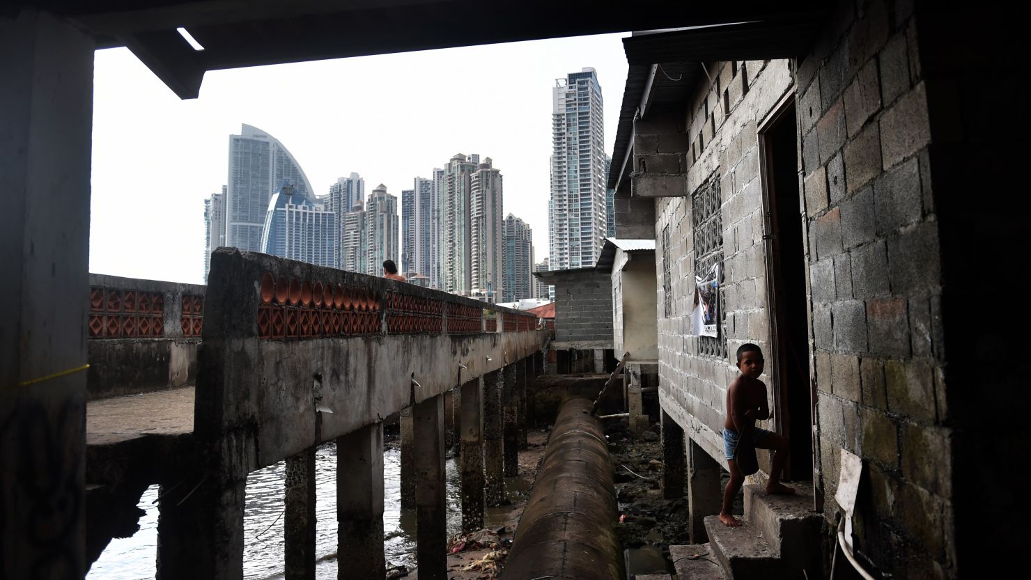 A boy walks into his house in Panama City's Boca La Caja neighborhood -- overlooked by new high-rise towers.