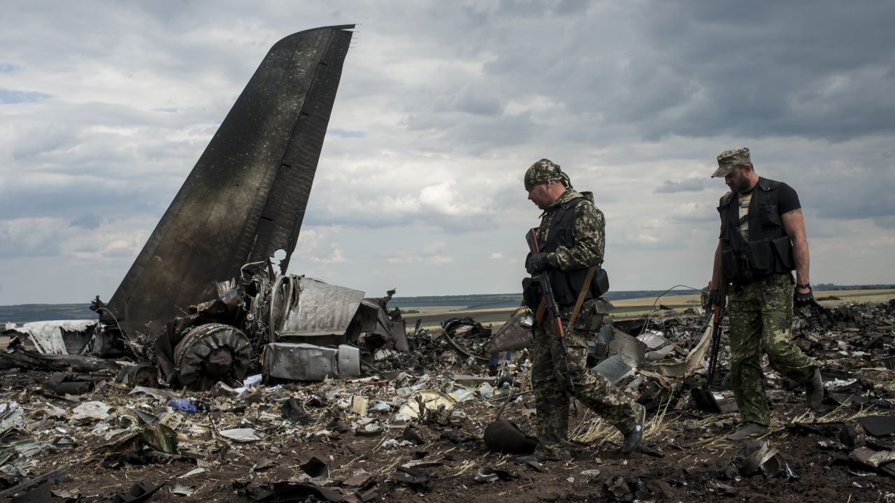 Pro-Russian fighters walk passed the site of remnants of a downed Ukrainian army aircraft on June 14,