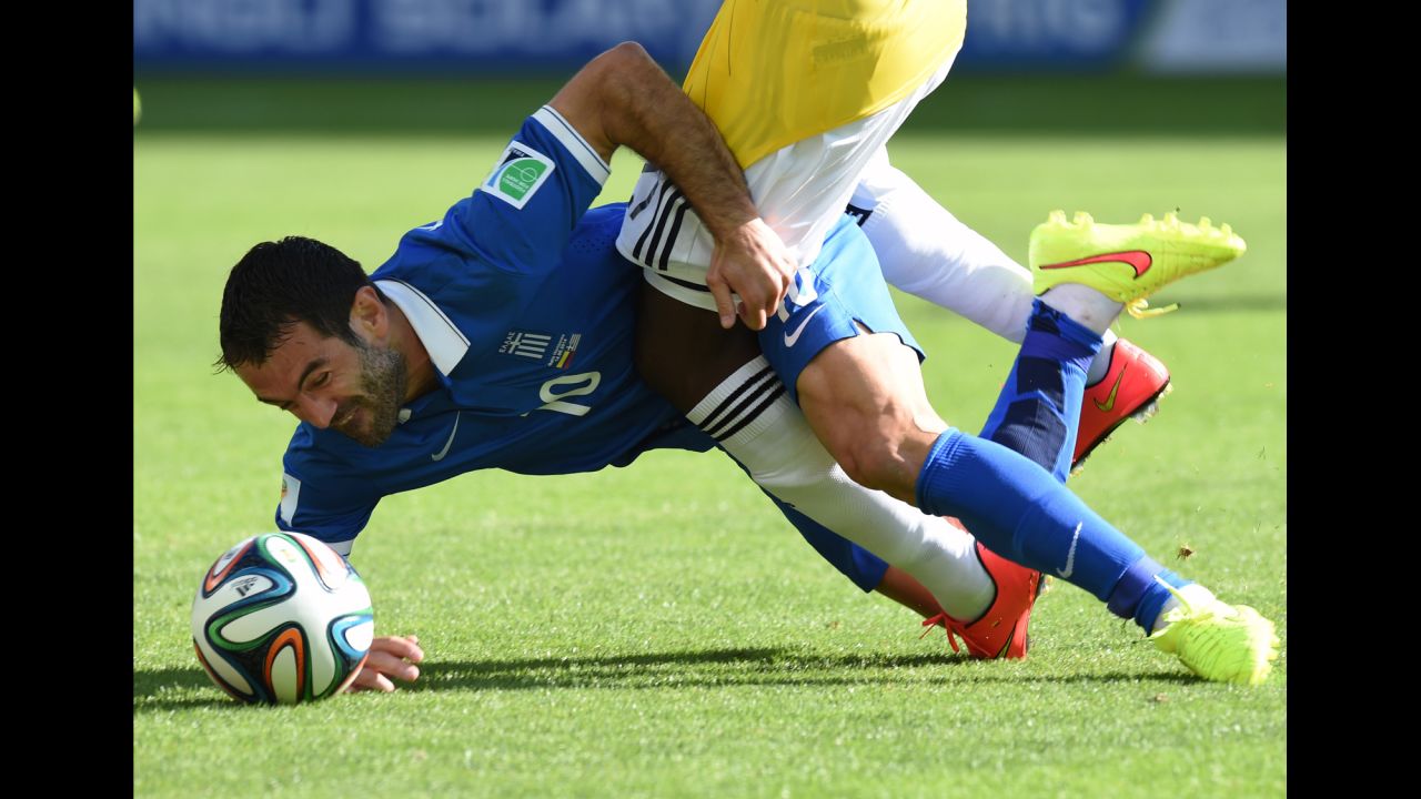 Greece midfielder Giorgos Karagounis tumbles to the ground as he tussles with Colombia forward Jackson Martinez.