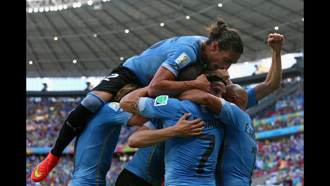 Martin Caceres piles on his Uruguay teammates as they celebrate Cavani's first-half goal. 