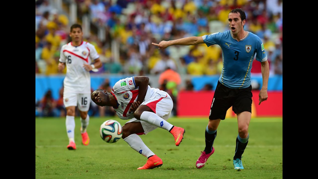 Uruguay defender Diego Godin, right, gestures as Costa Rica forward Joel Campbell, center, falls. 