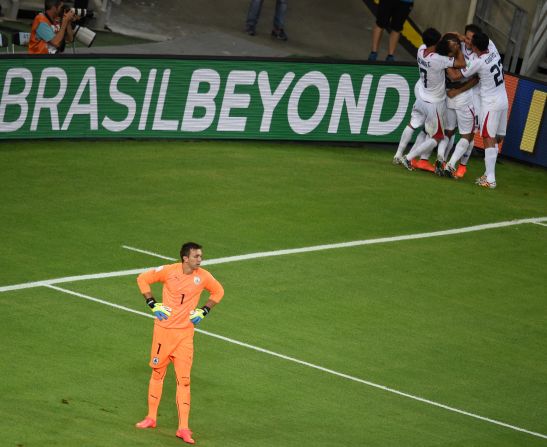 Uruguay goalkeeper Fernando Muslera, left, looks on as Costa Rica's players celebrate their team's late winner, scored by substitute Marco Urena, on June 14 in Fortaleza, Brazil. Costa Rica won 3-1.