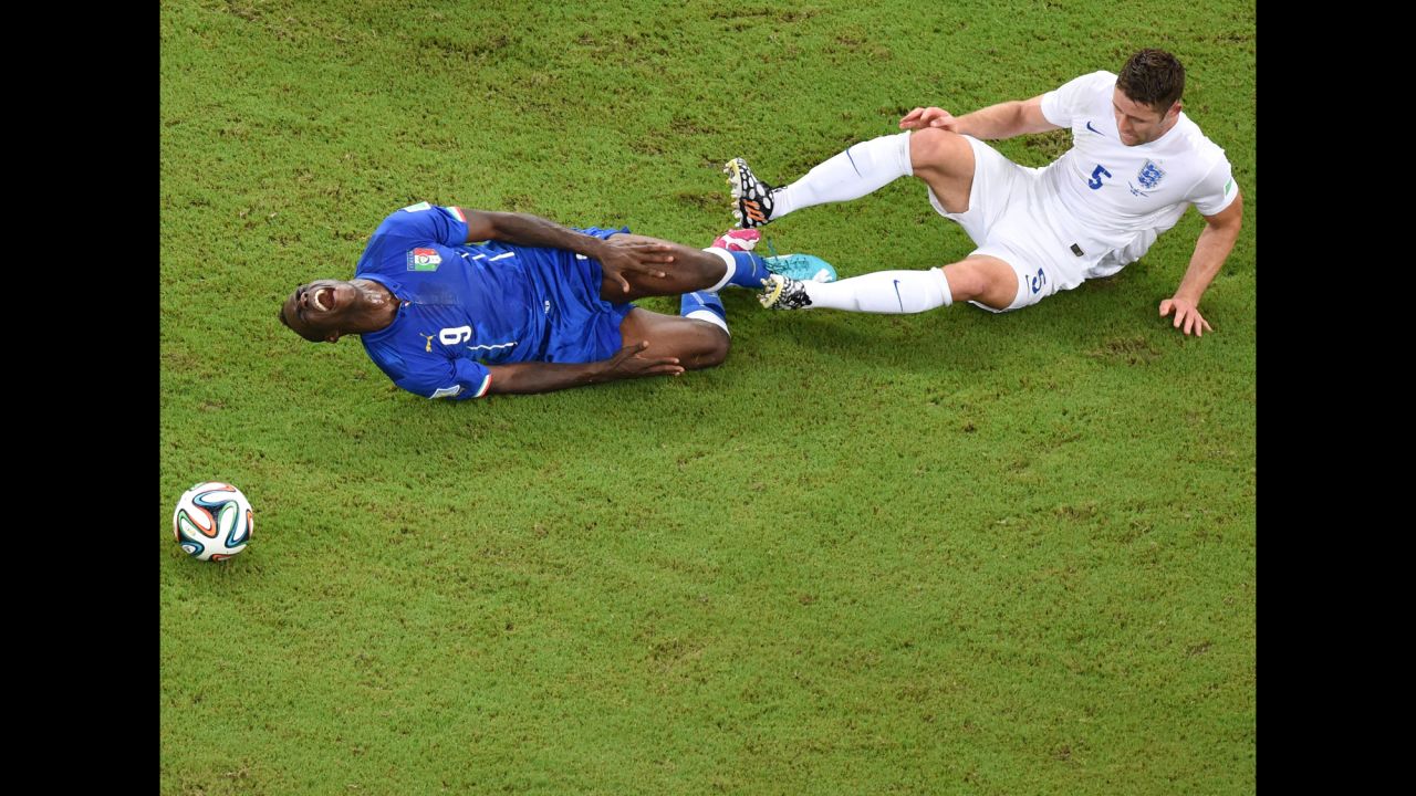 Italy forward Mario Balotelli, left, reacts following a tackle by England defender Gary Cahill.