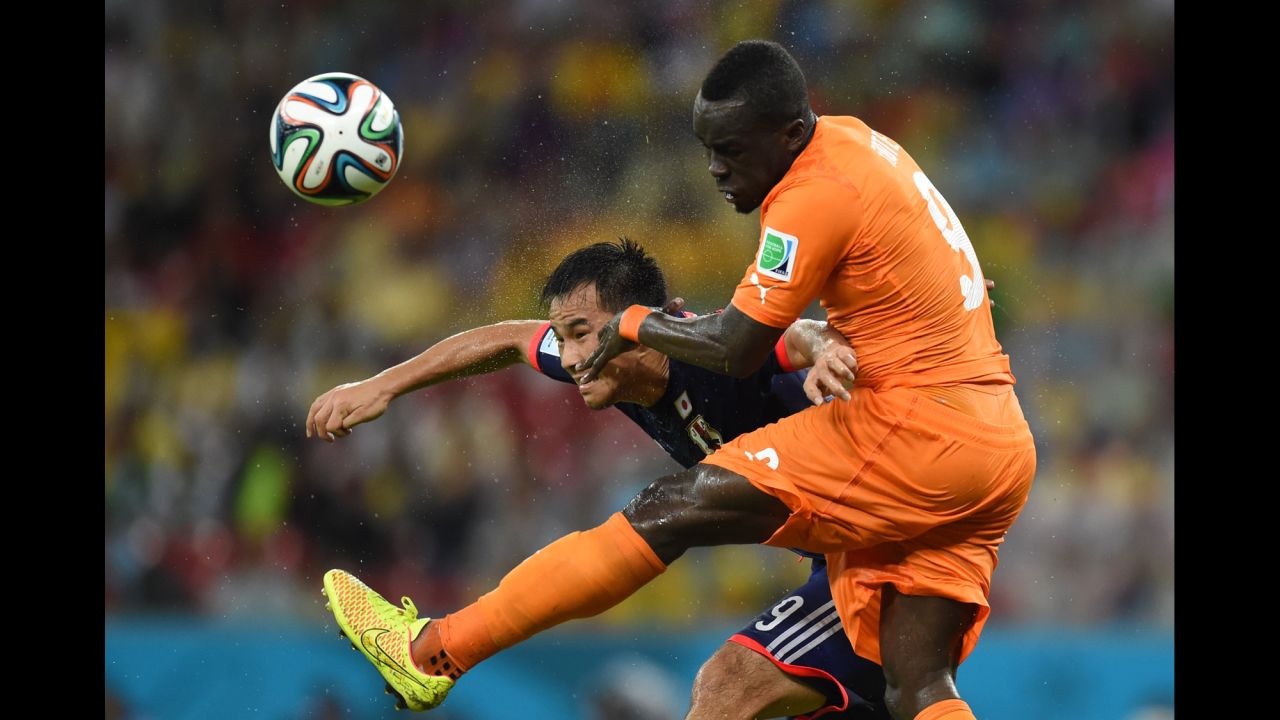 Japan forward Shinji Okazaki, left, heads the ball past Ivory Coast midfielder Cheick Tiote.