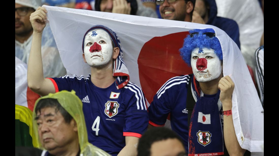 Japan fans protect themselves from the Brazilian rain with a Japanese flag.