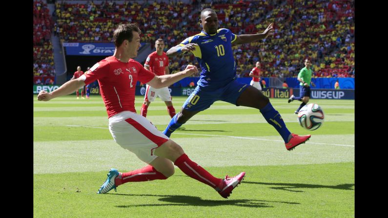 Switzerland defender Stephan Lichtsteiner, left, crosses the ball past Ecuador midfielder Walter Ayovi.
