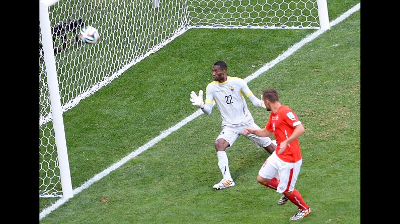 Substitute Haris Seferovic, right, scores Switzerland's injury-time winner past Ecuador goalkeeper Alexander Dominguez in the World Cup Group E match at Estadio Nacional on June 15 in Brasilia, Brazil. 