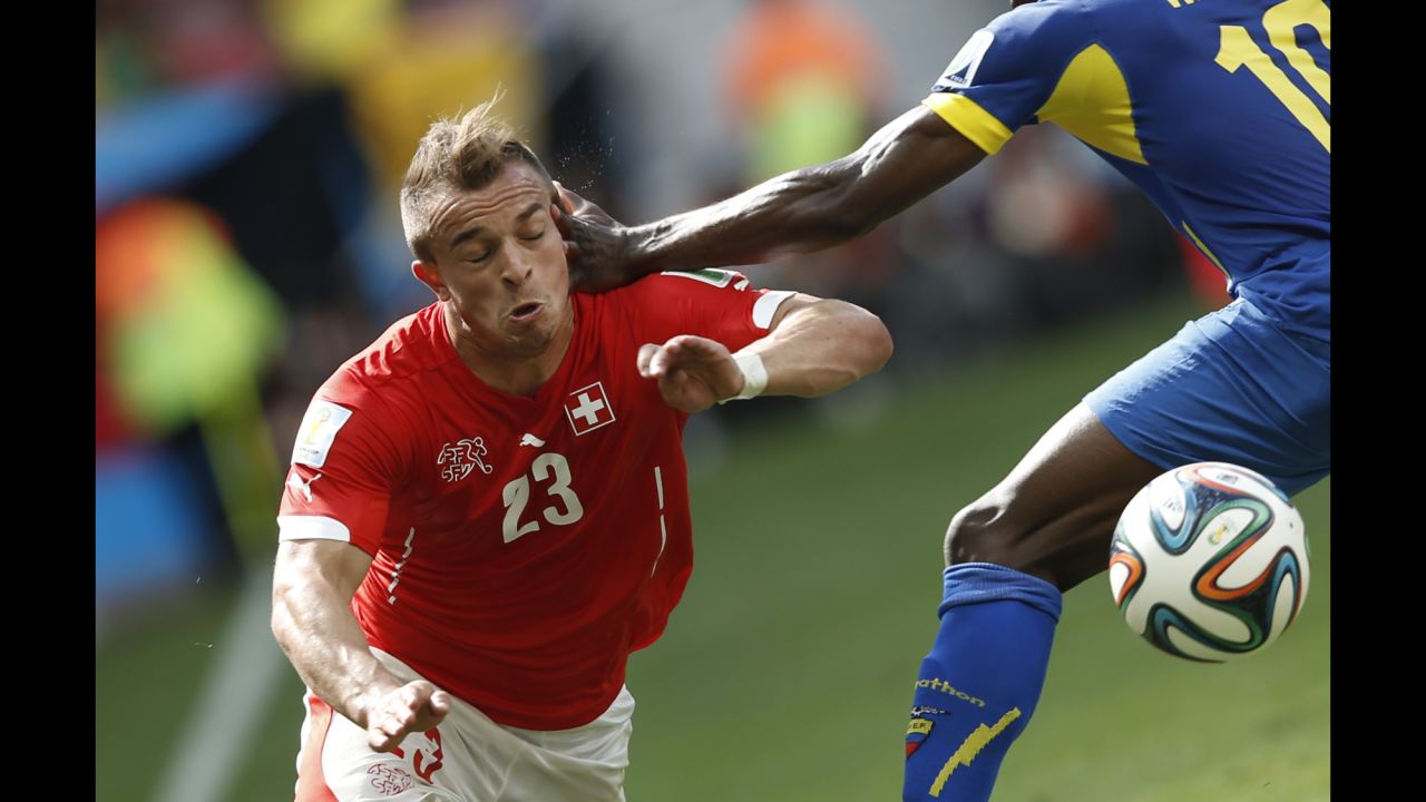 Switzerland midfielder Xherdan Shaqiri, left, goes to ground under a challenge from Ecuador's Walter Ayov.