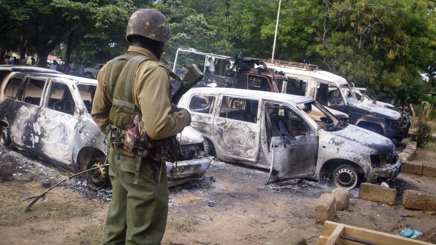 A member of the Kenyan security forces observes the remains of vehicles destroyed by militants, in the village of Kibaoni just outside the town of Mpeketoni, about 100 kilometers (60 miles) from the Somali border on the coast of Kenya Monday, June 16, 2014.