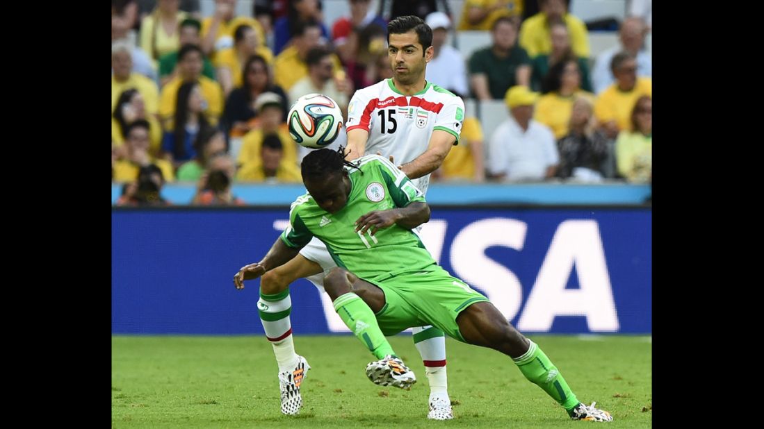 Iranian defender Pejman Montazeri (No. 15) challenges Nigeria's Victor Moses.