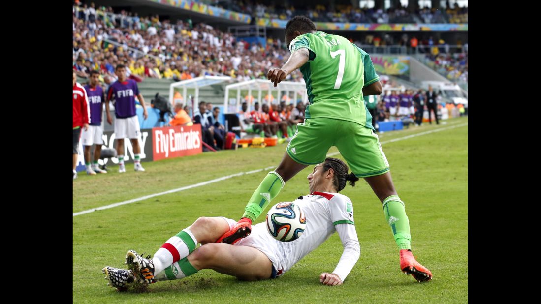 Iran's Andranik Teymourian slides under Nigeria's Ahmed Musa to take the ball away.